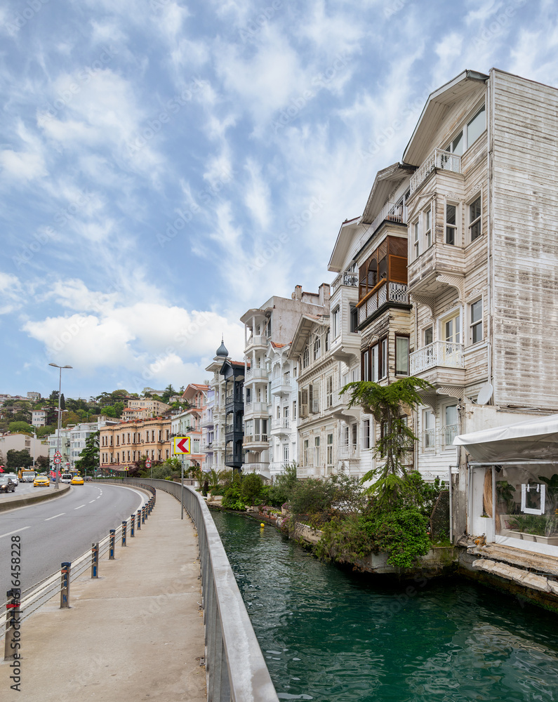 Wooden traditional residential buildings by a narrow water canal near Bosphorus strait, in Arnavutkoy neighborhood, Besiktas district, Istanbul, Turkiye, in a sunny spring day