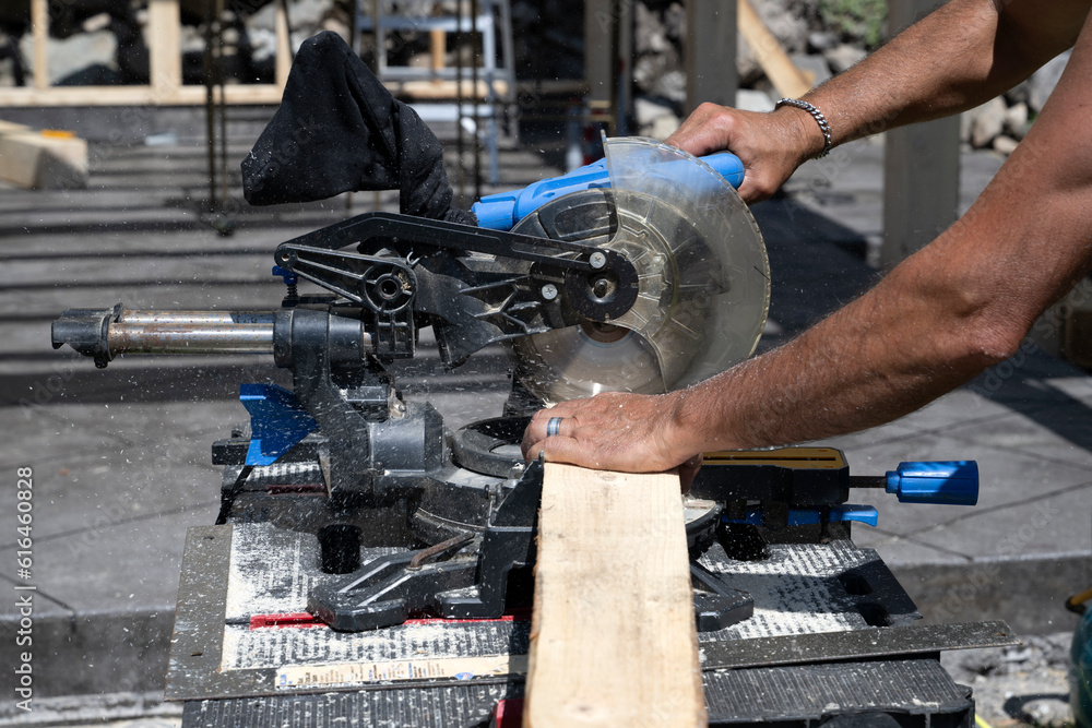 A man cutting a pice of wood with an electric saw A man cutting a pice of wood with an electric saw
