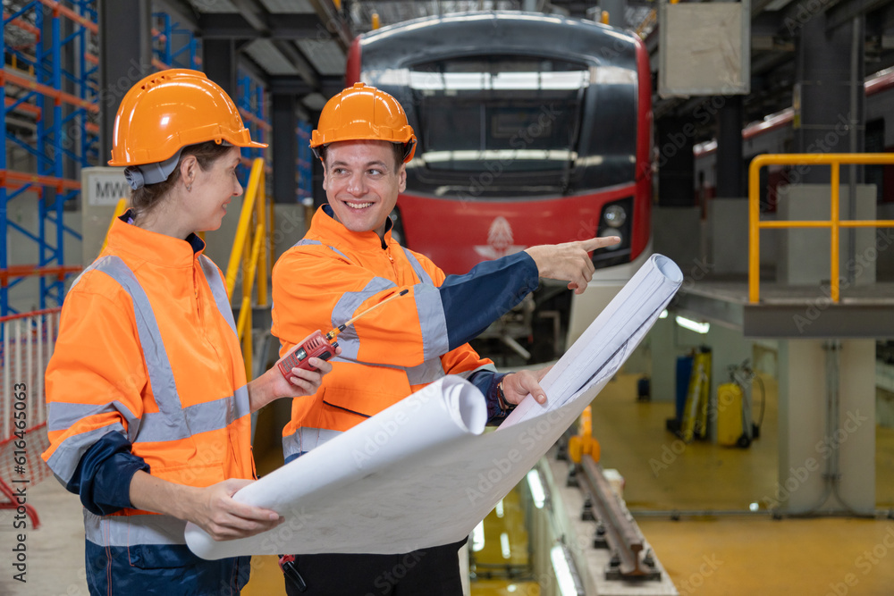 Two engineers check the spare parts list from drawing, tablet and maintenance of public transport trains in Asia