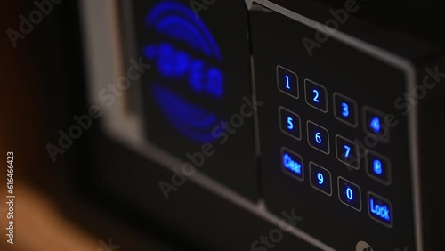 Man hand with a metal strongbox door close up. Unknown person entering numbers combination on electronic panel to lock modern safe. Male fingers pressing locker buttons using correct passcode.