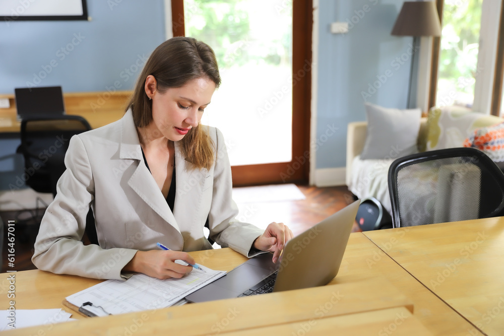 An attractive middle aged businesswoman sitting in front of laptop and working her business in the workspace An attractive middle aged businesswoman sitting in front of laptop and working her business in the workspace