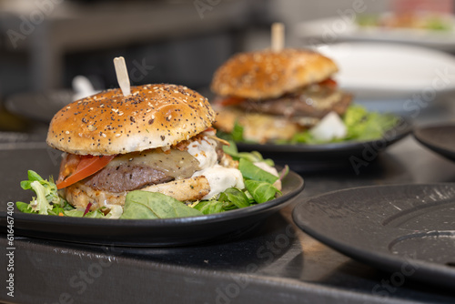 deux hamburger dont un en arrière plan dans une cuisine de bistrot