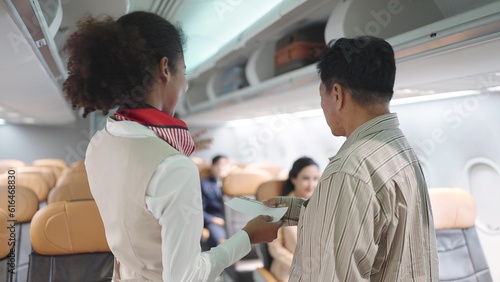 Back view of women flight attendant checking passenger's boarding pass and welcoming to the flight. Woman cabin crew greeting passengers on airplane service. Airways concept