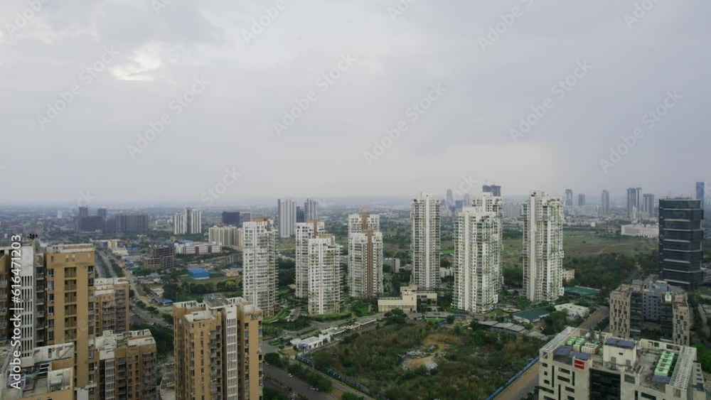 aerial drone shot panning full circle showing skyscraper towers residential office buildings with roads passing between to small houses in city of gurgoan on overcast cloudy monsoon evening aerial drone shot panning full circle showing skyscraper towers residential office buildings with roads passing between to small houses in city of gurgoan on overcast cloudy monsoon evening