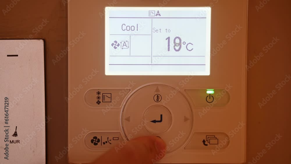 Closeup the man hand controls and presses the buttons The air conditioning and heating control panel for the apartment and office is located on a white wall. Close up Closeup the man hand controls and presses the buttons The air conditioning and heating control panel for the apartment and office is located on a white wall. Close up
