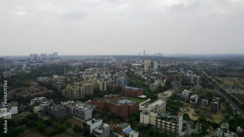 aerial drone shot decending over multi colored buildings in gurgoan with roads and parks on cloudy evening showing how large the city is aerial drone shot decending over multi colored buildings in gurgoan with roads and parks on cloudy evening showing how large the city is