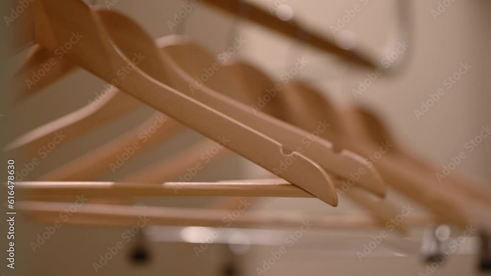 Empty wooden clothing hangers hanging on metal rack close up view. Shopping and discount concept. Empty wooden clothing hangers hanging on metal rack close up view. Shopping and discount concept.