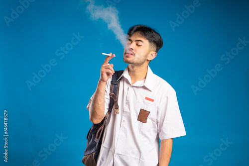 The high school student exhaled a puff of smoke from his mouth. Nicotine addiction. International Smoking Cessation Day concept. photo