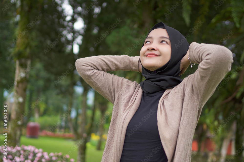 asian hijab woman relaxing  holding head in the park