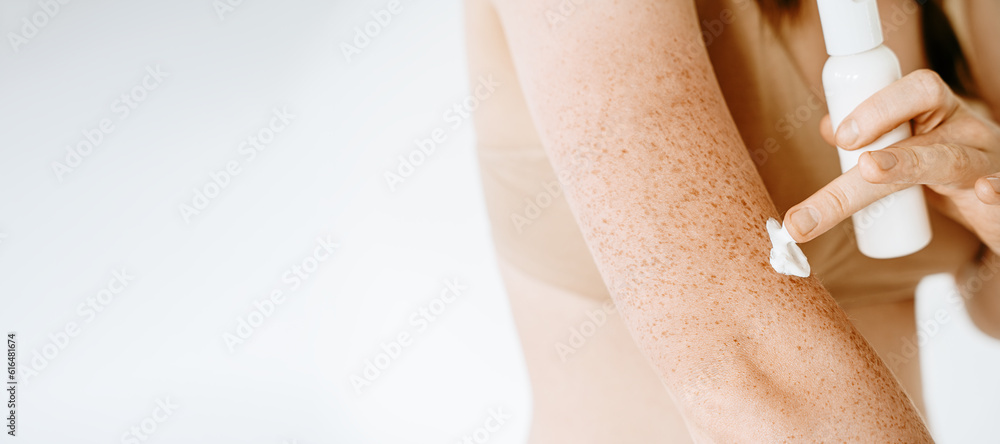 Φωτογραφία Woman with freckles applying cream on her body, skin protection from the sun, moisturizing the skin
