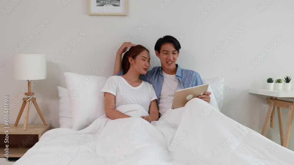 Young couple watching tv series laughing happily using tablet and sitting on sofa bed Young couple watching tv series laughing happily using tablet and sitting on sofa bed