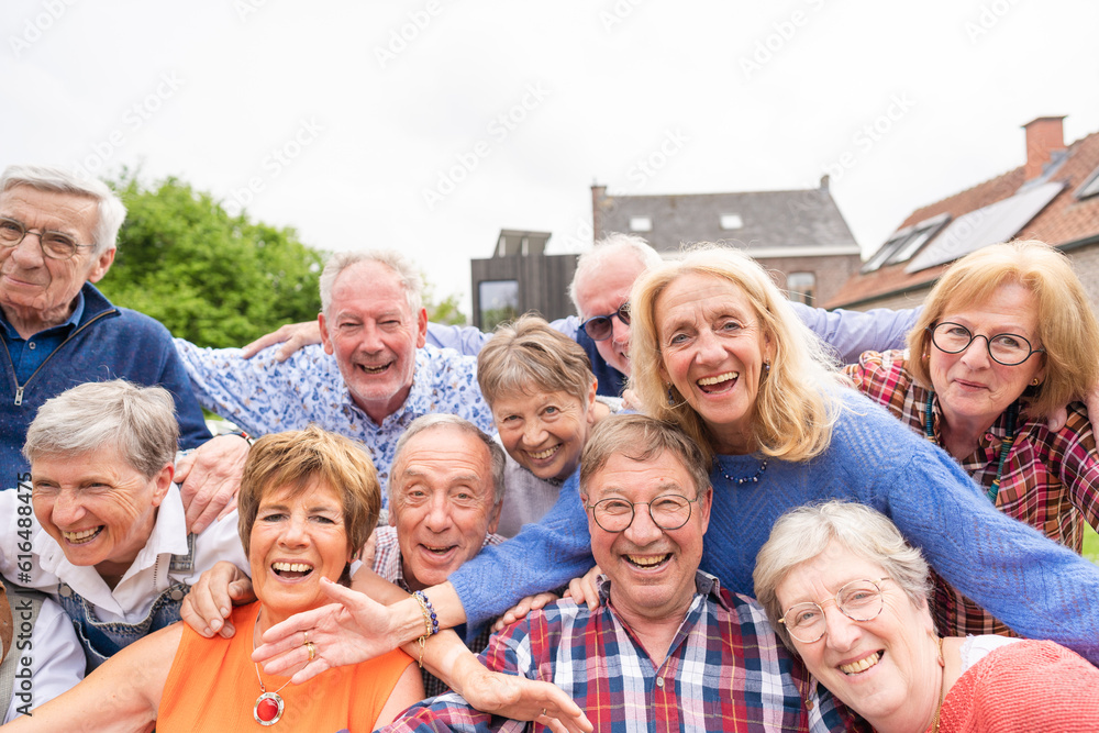 Obraz premium Carefree and happy elderly friends embrace joyfully and taking selfie outdoor in the garden.