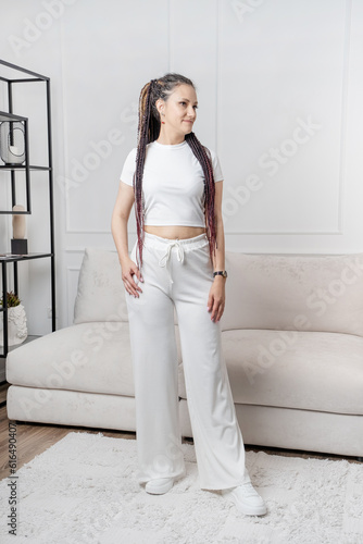 Fashionable young beautiful woman with dreadlocks posing in interior