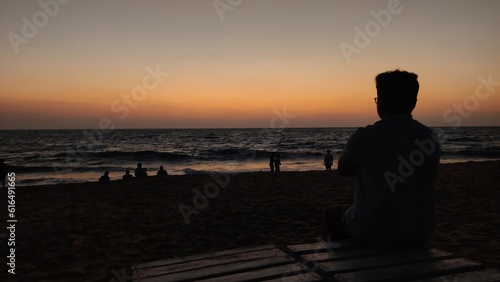 silhouette of a person sitting on a bench looking at the sunset on the beach