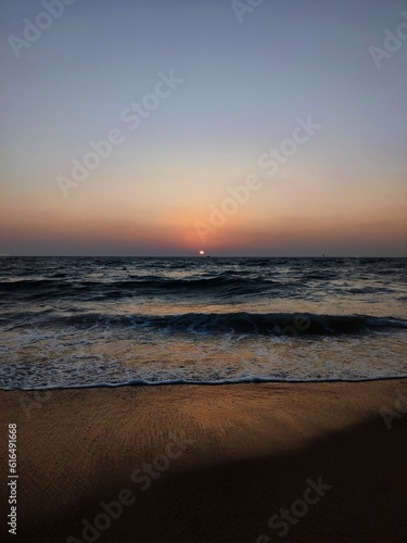 sunset at the beach with the evening sky and the waves of the ocean water