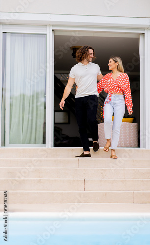 Young couple woling down on stairs by the swimming pool in the house backyard photo