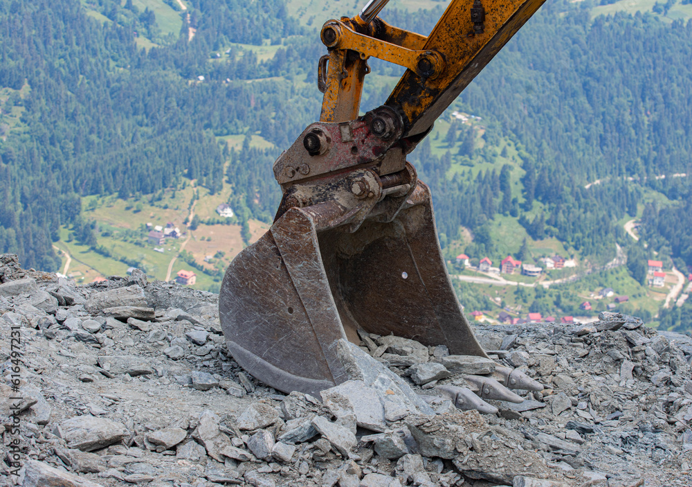 Fototapeta premium Heavy road construction elevator machine. Excavator shovel at construction site.