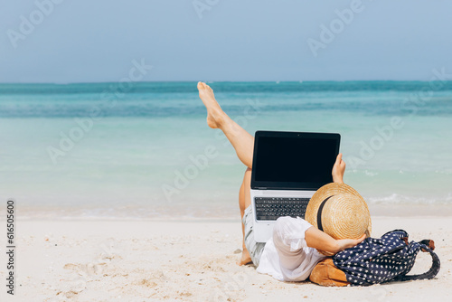 Business woman working with computer on the beach. Freelance concept. Pretty young woman using laptop on tropical beach