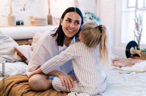 Little girl whispering to mom before bed time