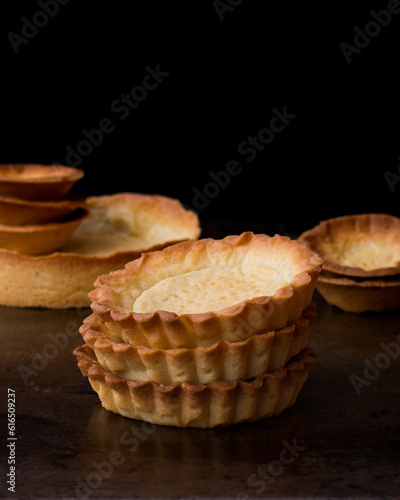 Stacked shortcrust pastry tartlets on a black background
