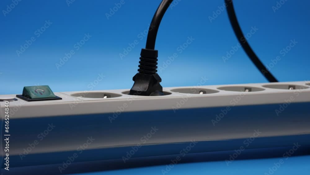 Plug In The Socket Of An Electric Extension Cord On Blue Background. Panning Dolly Slider Shot. Close Up. 4k, 60 FPS.