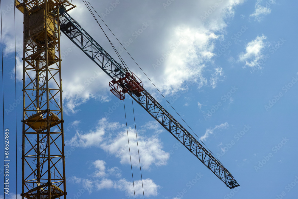 A yellow construction crane on a cloudy sky background