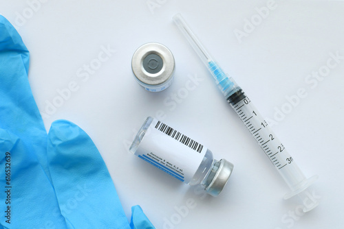 Foto A syringe needle with generic vaccine booster in vial with blank label - mock up