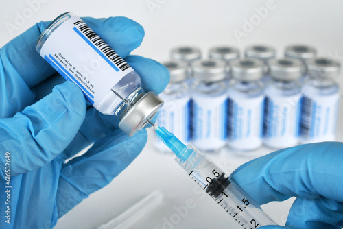 Medical personnel filling a syringe needle with generic vaccine booster from vial with blank label - mock up copy space  photo
