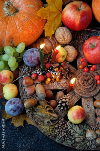 Wiccan altar for Mabon sabbat. wheel of the year, candles, fruits, pumpkins, flowers, autumn leaves on dark table. Witchcraft, esoteric spiritual ritual. autumn equinox holiday. harvest time. top view