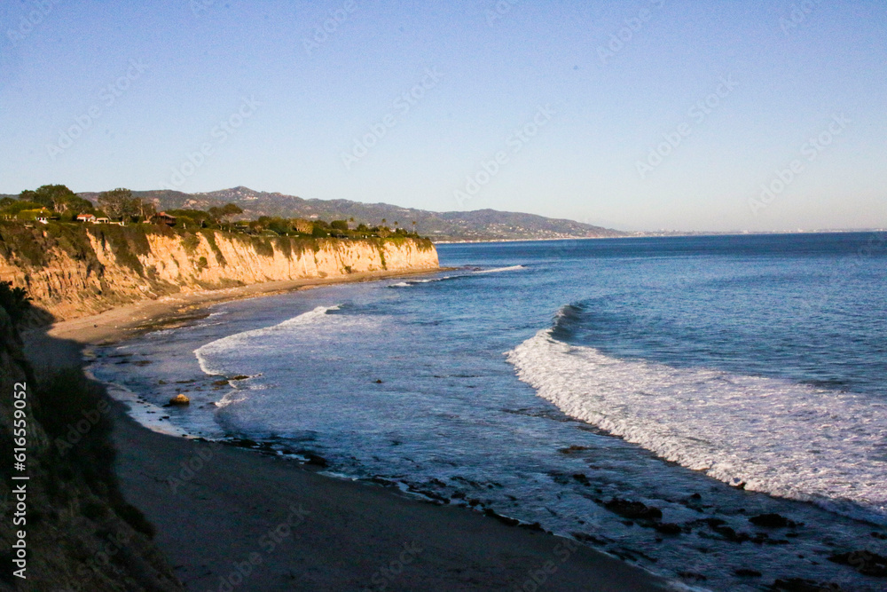 Sunsets on mountainous coastline by ocean as waves crash in Sunsets on mountainous coastline by ocean as waves crash in