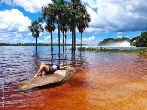 mujer acostada sobre piedra laguna de canaima  photo