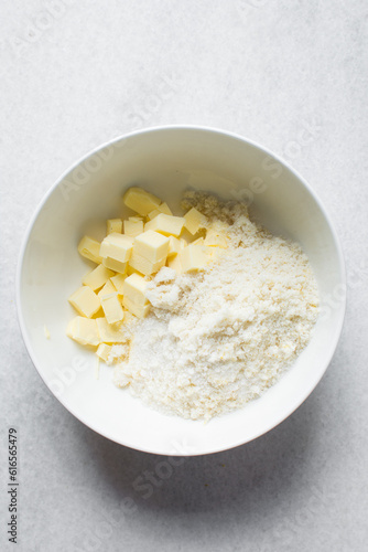 cubes of butter and sugar in a white bowl, organic butter  and granulated sugar about to be creamed in a white mixing bowl, process of making cake