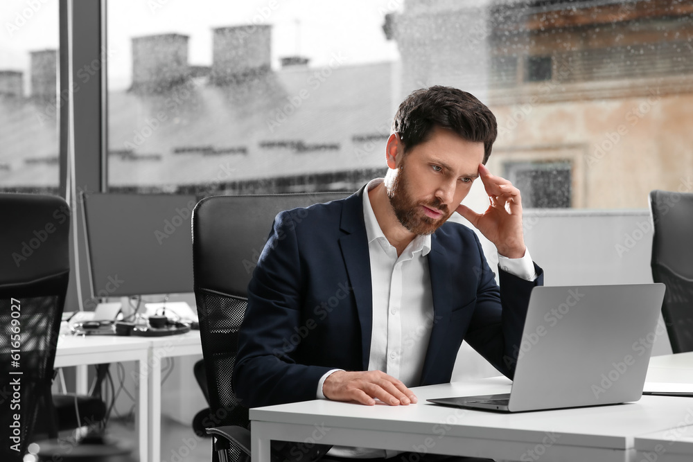 Man working on laptop at white desk in office