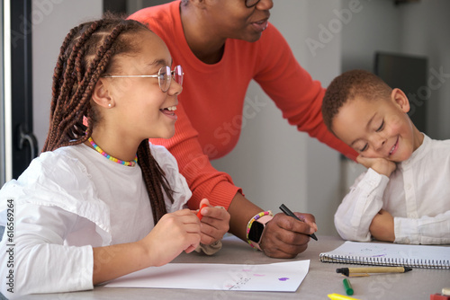 African mother painting with their children during the freetime. Horizontal extended family. photo