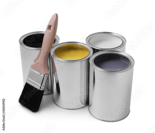 Cans of different paints with brush on white background