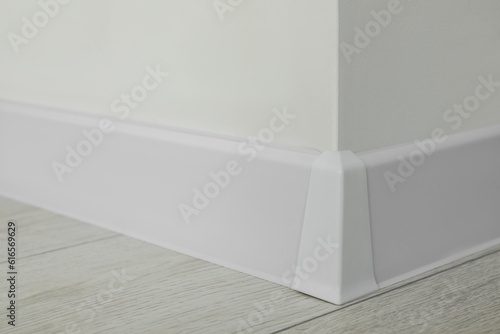 White plinth with connector on laminated floor near wall indoors  closeup