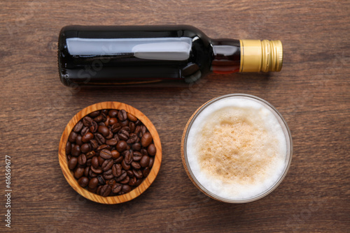 Bottle of delicious syrup, glass of coffee and beans on wooden table, flat lay