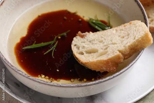 Balsamic vinegar with oil, rosemary and bread slice in bowl, closeup