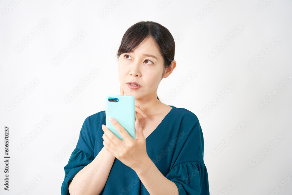 スマートフォンを持って考えるミドルエイジ女性 白背景 スマートフォンを持って考えるミドルエイジ女性 白背景