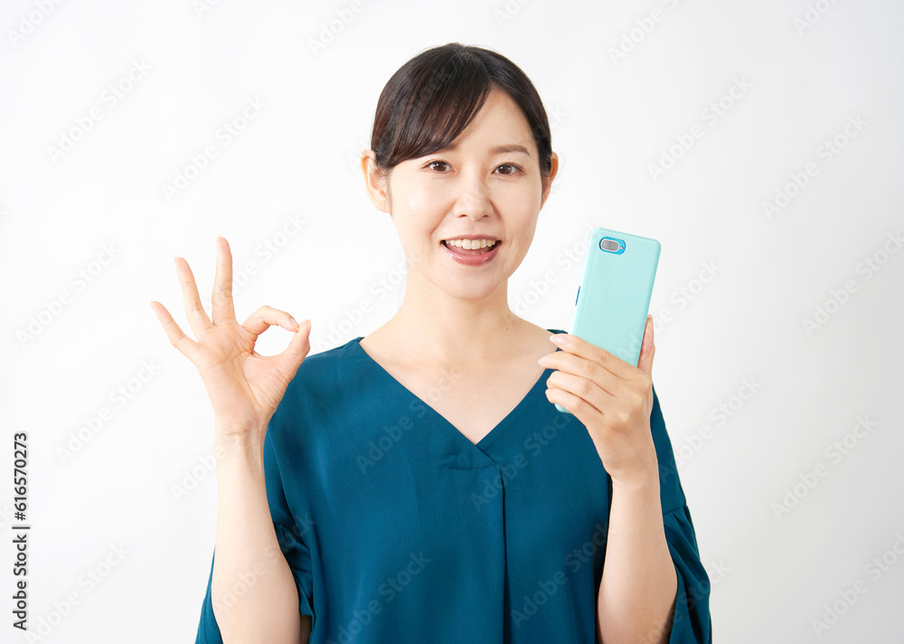 スマートフォンを持ってOKサインするミドルエイジ女性　白背景