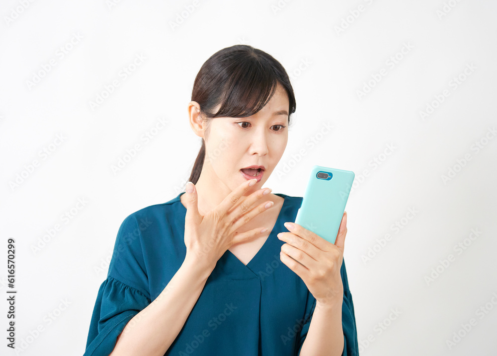 スマートフォンを持って驚くミドルエイジ女性 白背景 スマートフォンを持って驚くミドルエイジ女性 白背景