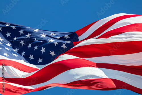 Closeup of American flag blowing in the wind with blue sky