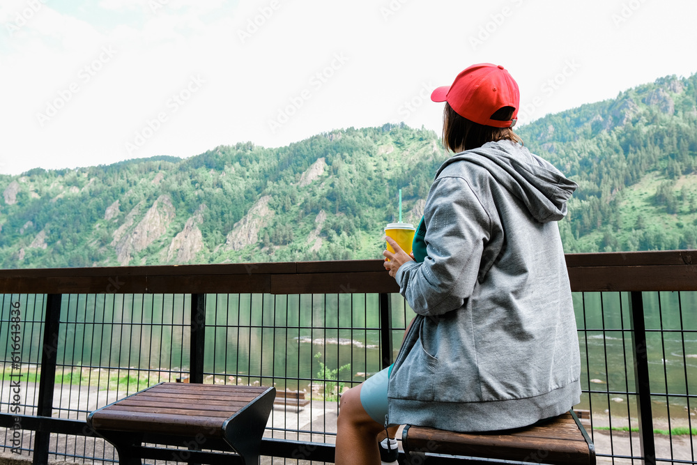 Female traveler in red hat sitting bench and looking at a beautiful mountain,sky field and nature view. Sit back. Female traveler in red hat sitting bench and looking at a beautiful mountain,sky field and nature view. Sit back.