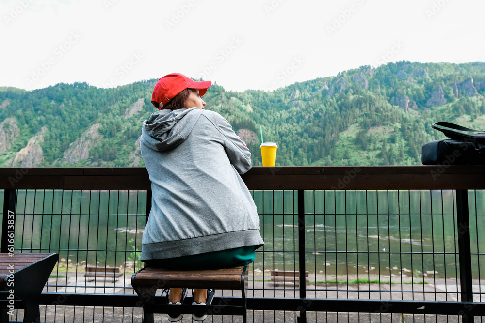 Female traveler in red hat sitting bench and looking at a beautiful mountain,sky field and nature view. Sit back.