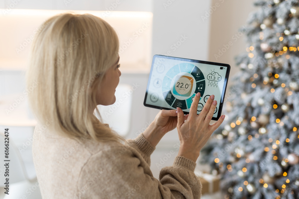 Modern home smart automation app on tablet display in woman hands at Christmas Modern home smart automation app on tablet display in woman hands at Christmas