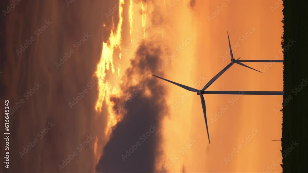 This captivating video captures wind turbines silhouetted against a breathtaking sunset. The golden hues of the setting sun illuminate the sky, creating a stunning backdrop for the towering turbines a This captivating video captures wind turbines silhouetted against a breathtaking sunset. The golden hues of the setting sun illuminate the sky, creating a stunning backdrop for the towering turbines a