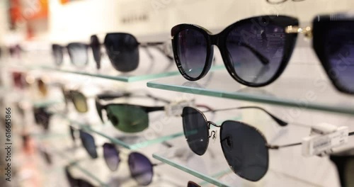 Stylish trendy sunglasses on shelf in store. Selection of quality sunglasses photo