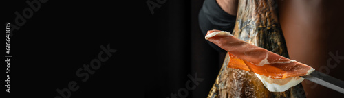 jamon slices, dry italian prosciutto, raw pork ham on a dark background, Long banner format photo