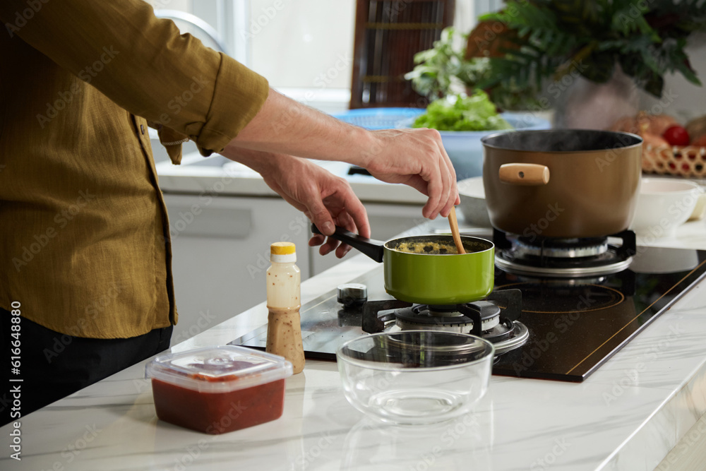 Cropped image of man cooking dinner at kitchen stove Cropped image of man cooking dinner at kitchen stove