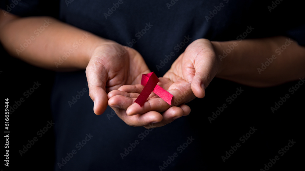 A beautiful red ribbon is on hand is the symbol of aid, support and campaign.A hand is holding a red ribbon. Ribbons have many differences colours such as blue, white, pink red orange white and purple A beautiful red ribbon is on hand is the symbol of aid, support and campaign.A hand is holding a red ribbon. Ribbons have many differences colours such as blue, white, pink red orange white and purple